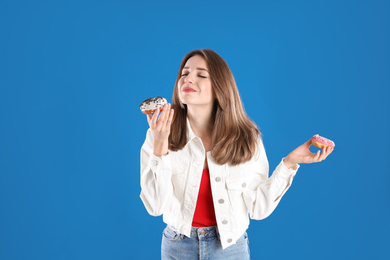 Beautiful young woman with donuts on blue background