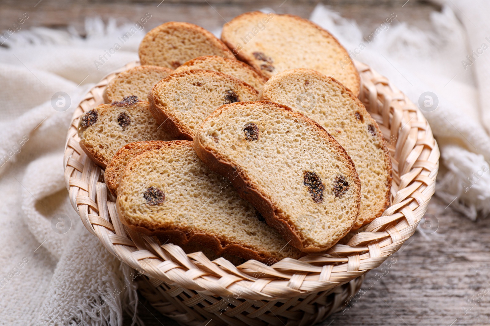 Photo of Sweet hard chuck crackers with raisins in wicker basket on wooden table, closeup