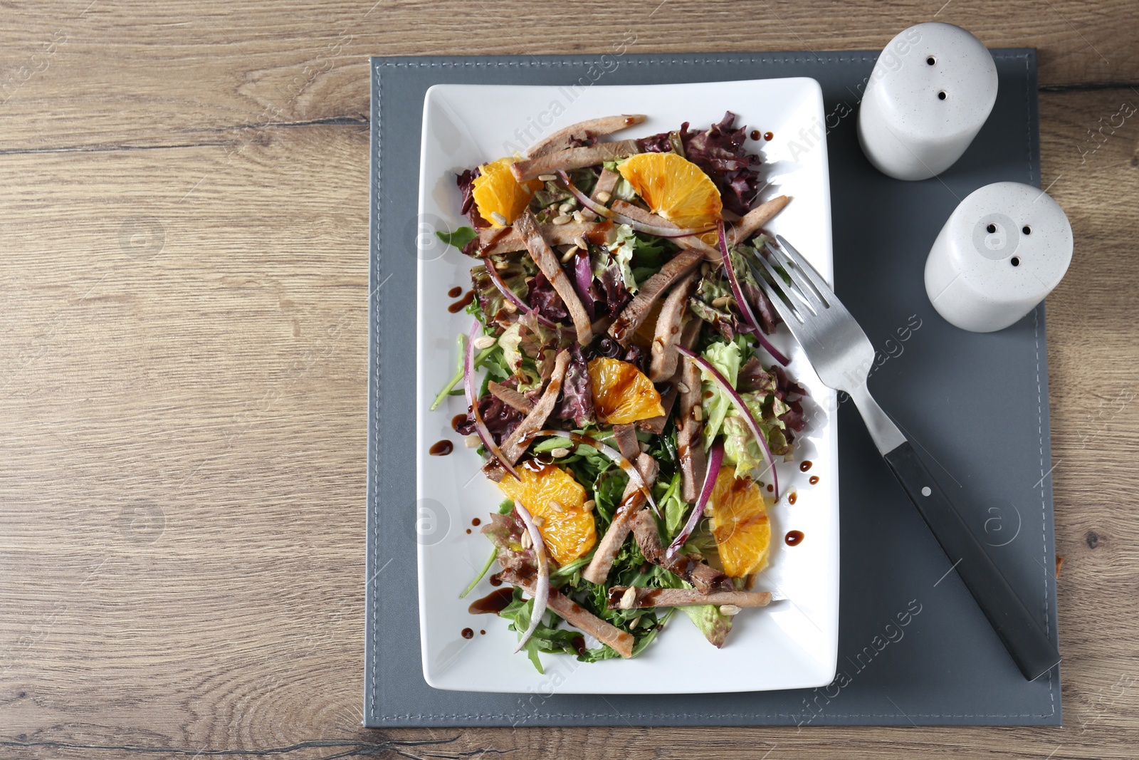 Photo of Delicious salad with beef tongue, orange, onion and fork served on wooden table, flat lay. Space for text