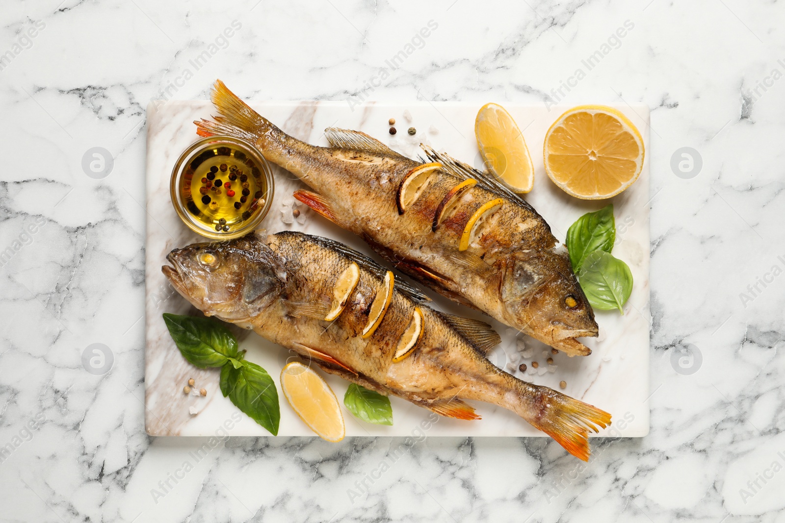 Photo of Tasty homemade roasted perches served on white marble table, top view. River fish