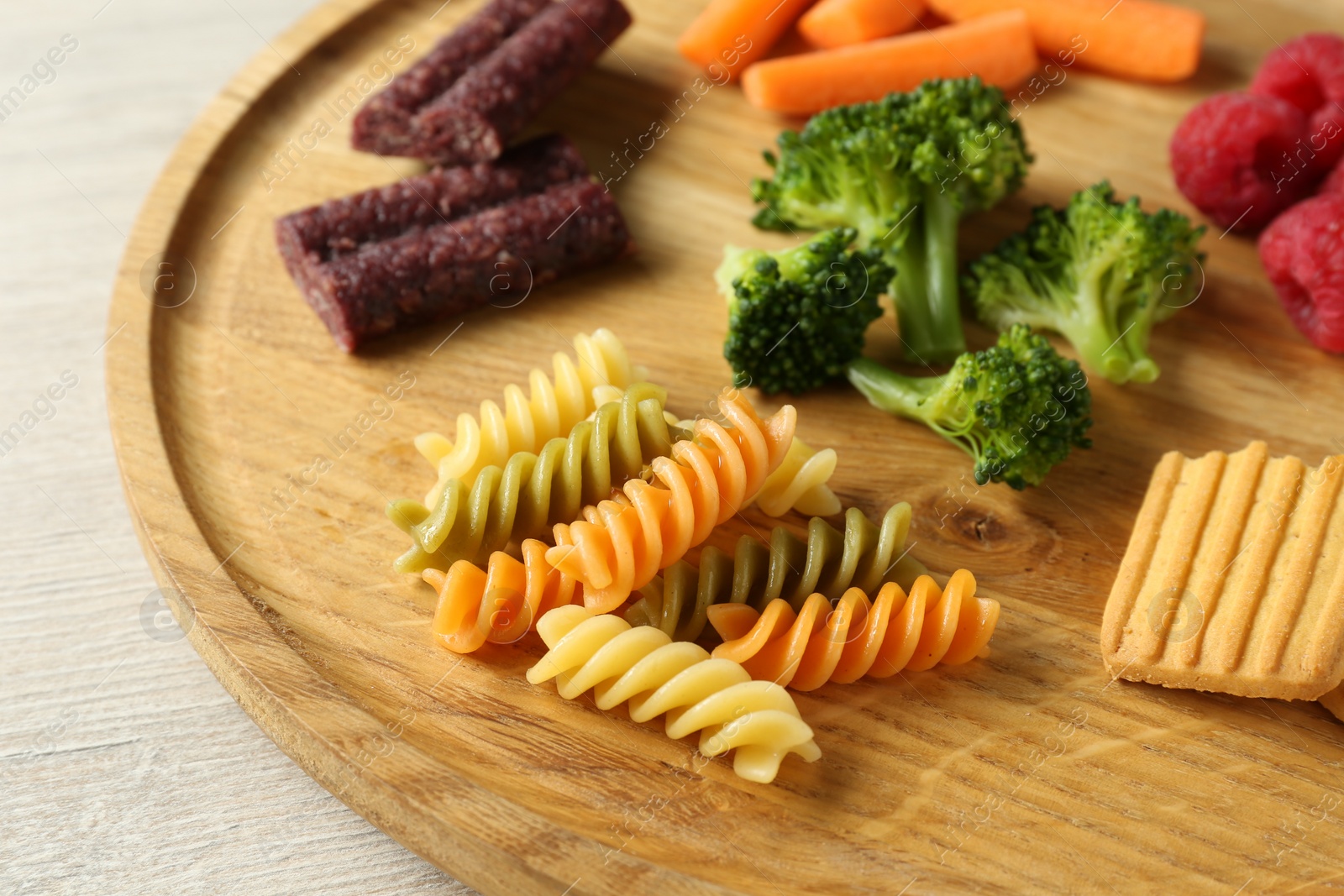 Photo of Wooden board with different finger foods for baby on table, closeup
