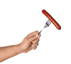 Man holding fork with grilled sausage on white background, closeup. Barbecue food