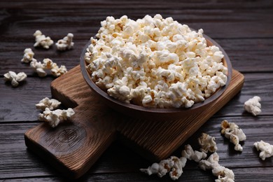 Photo of Tasty popcorn on black wooden table, closeup