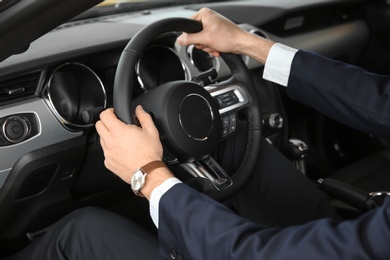 Photo of Young businessman sitting in driver's seat of auto. Buying new car