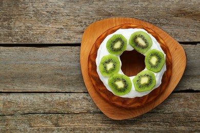 Photo of Homemade yogurt cake with kiwi and cream on wooden table, top view. Space for text