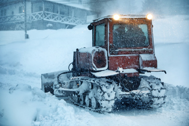 Tractor cleaning road in snowstorm. Winter season