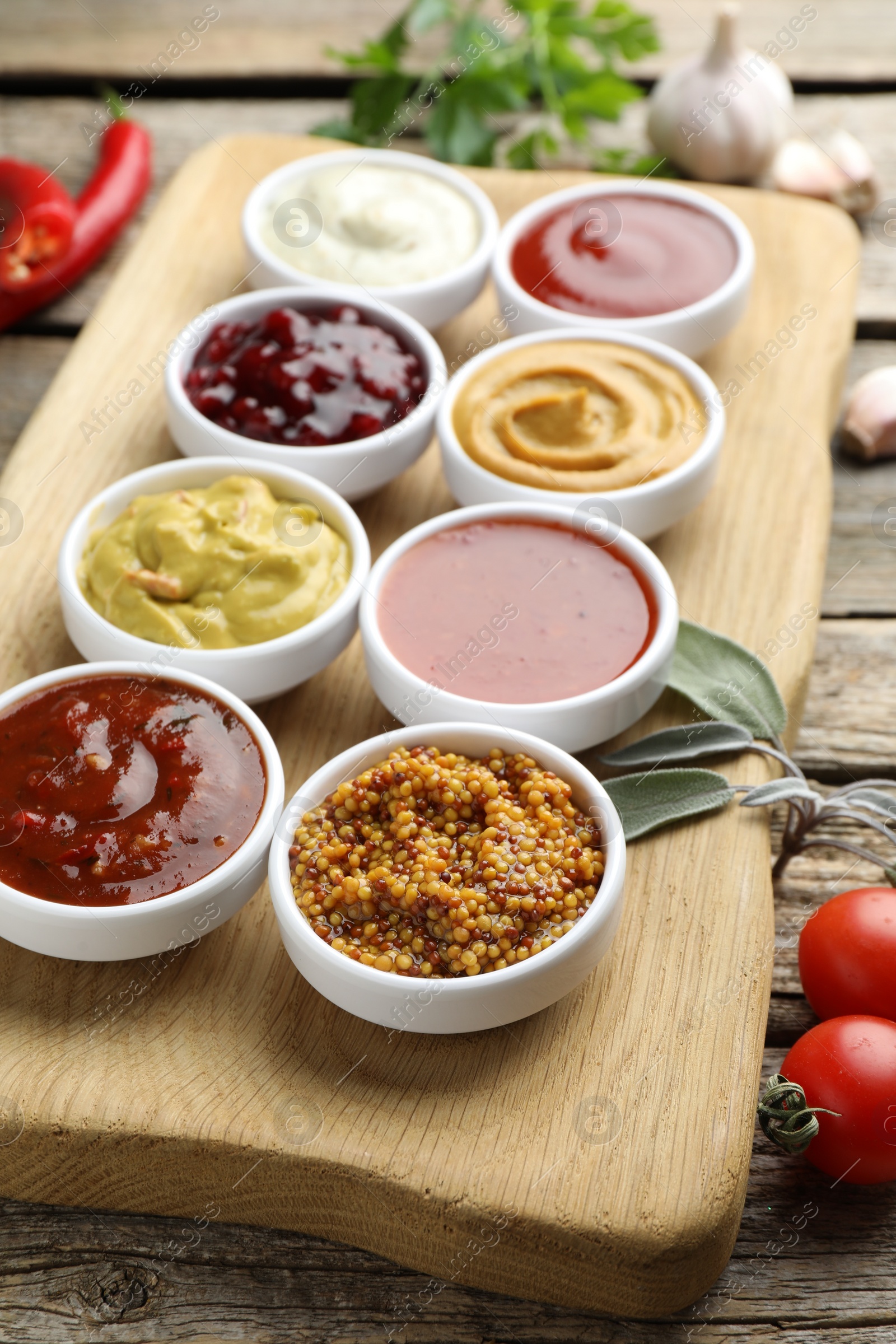 Photo of Different tasty sauces in bowls and ingredients on wooden table