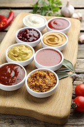 Different tasty sauces in bowls and ingredients on wooden table