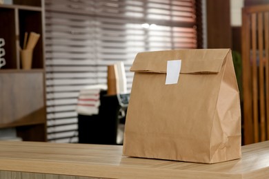 Paper bag on wooden counter in cafe, space for text