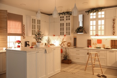 Photo of Small Christmas trees and festive decor in kitchen