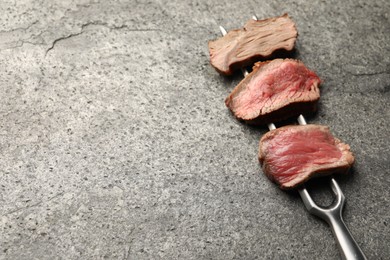 Photo of Delicious sliced beef tenderloin with different degrees of doneness on grey table. Space for text