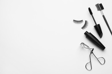 Composition with eyelash curler and mascara on white background, top view