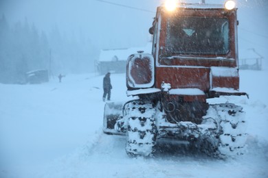Tractor cleaning road in snowstorm. Winter season
