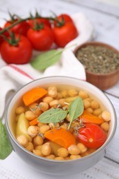 Photo of Tasty chickpea soup in bowl and spices on white wooden table