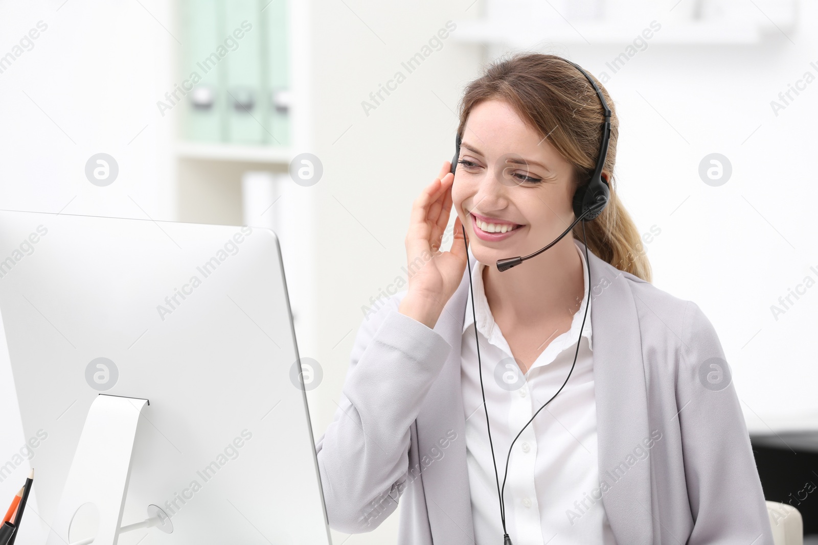 Photo of Young female receptionist with headset in office