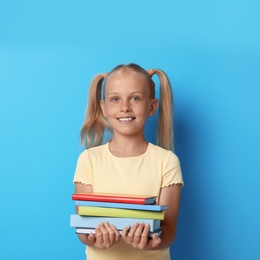 Photo of Portrait of cute little girl with books on blue background. Reading concept