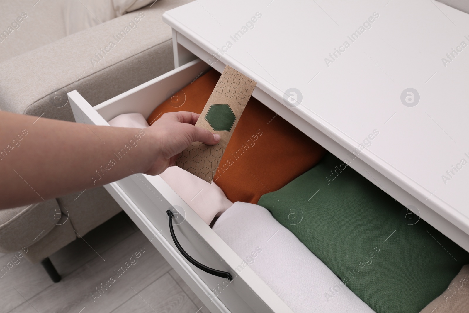 Photo of Woman putting scented sachet into drawer with clothes, closeup