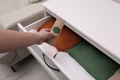 Photo of Woman putting scented sachet into drawer with clothes, closeup