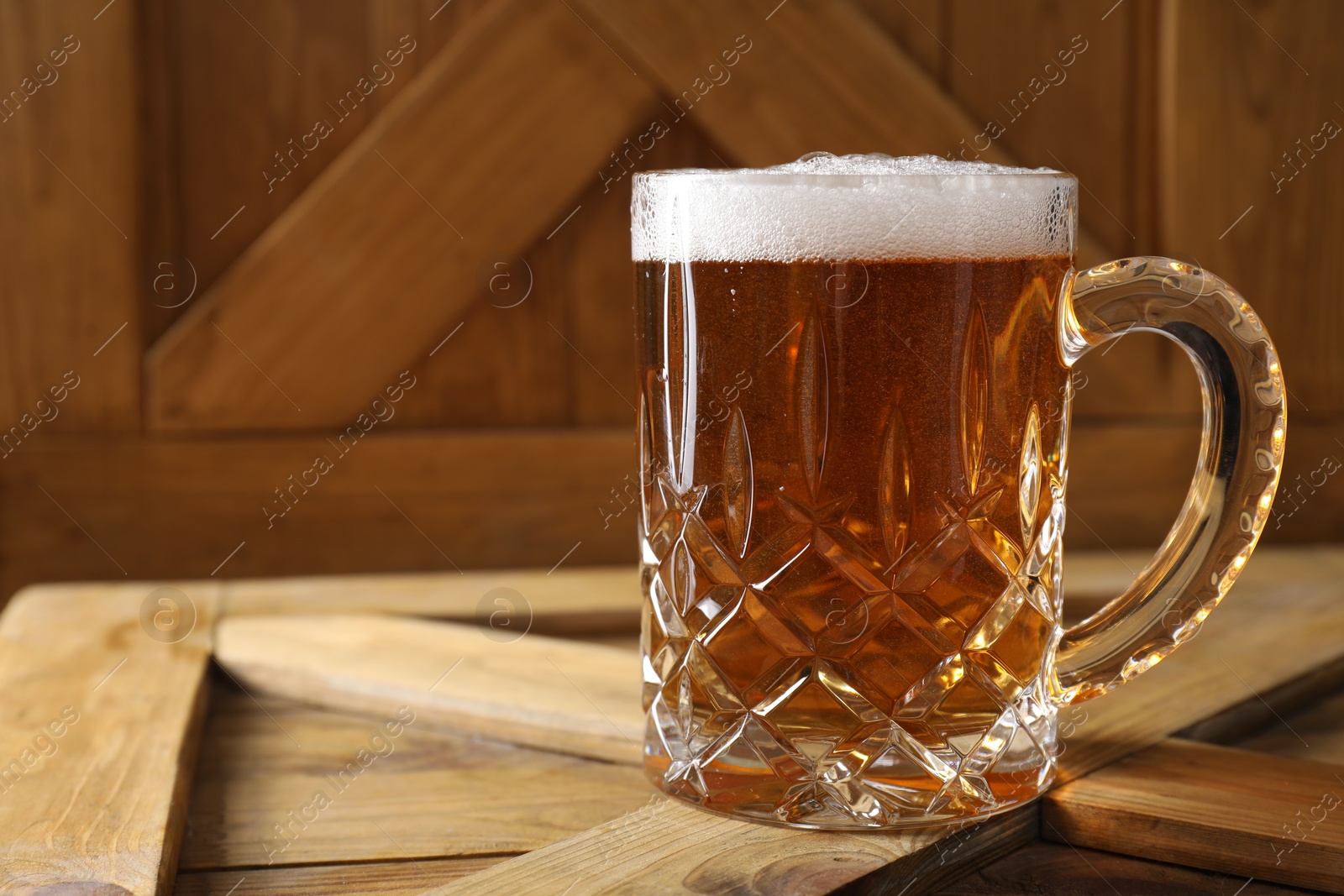 Photo of Mug with fresh beer on wooden crate, closeup. Space for text