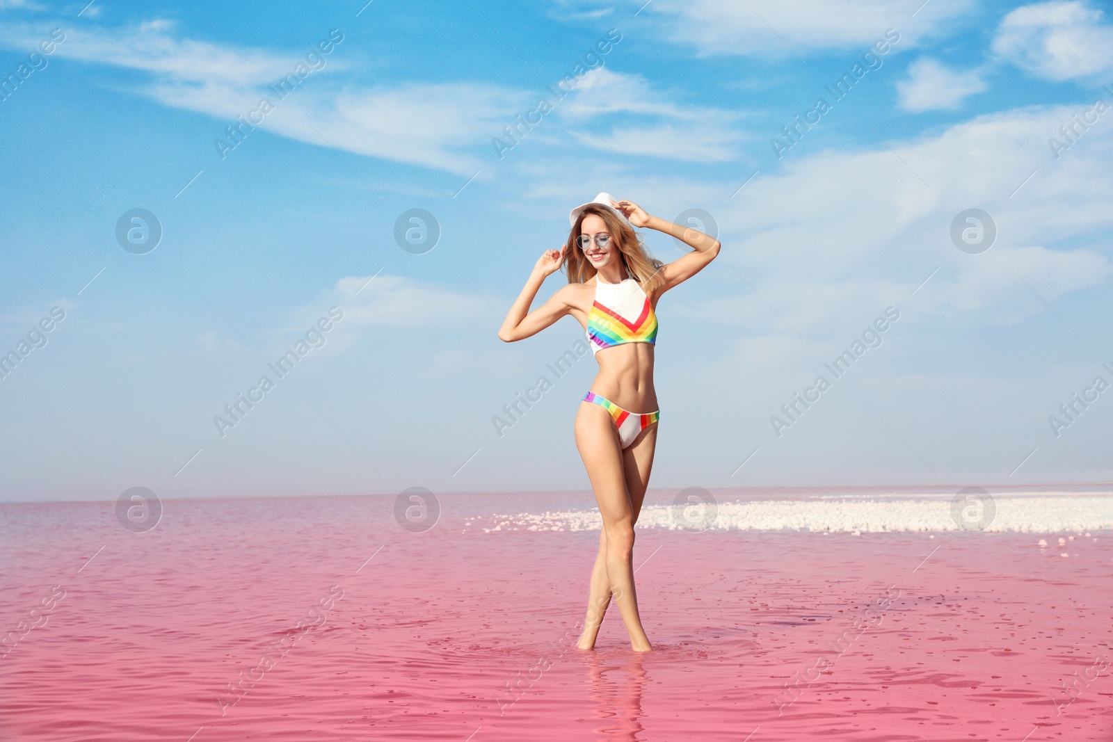 Photo of Beautiful woman posing in pink lake on sunny day