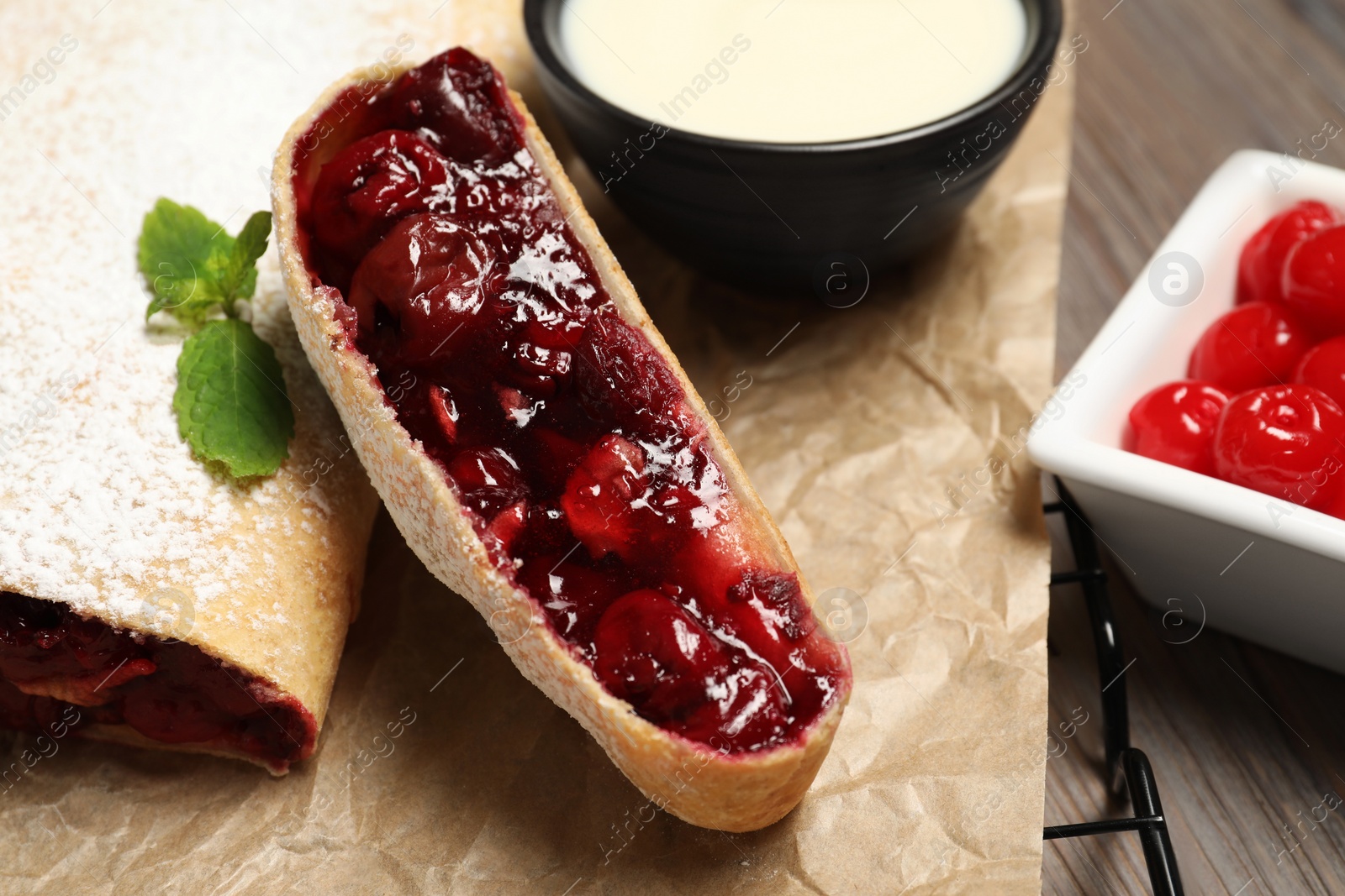 Photo of Delicious strudel with cherries on wooden table, closeup