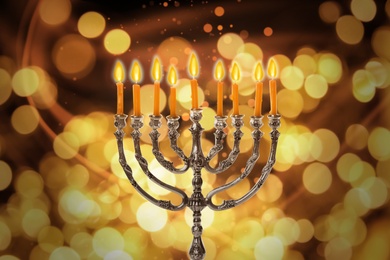 Image of Silver menorah with burning candles against blurred lights. Hanukkah celebration