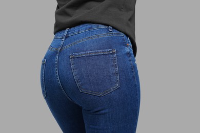 Photo of Woman in stylish jeans on grey background, closeup