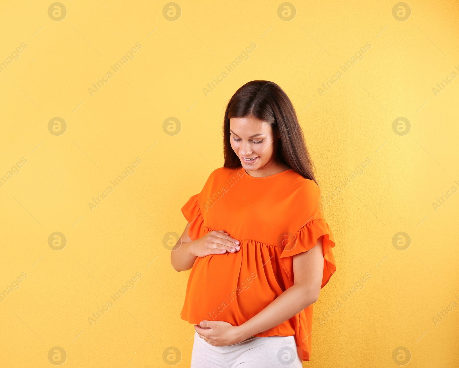 Photo of Happy pregnant woman posing on color background