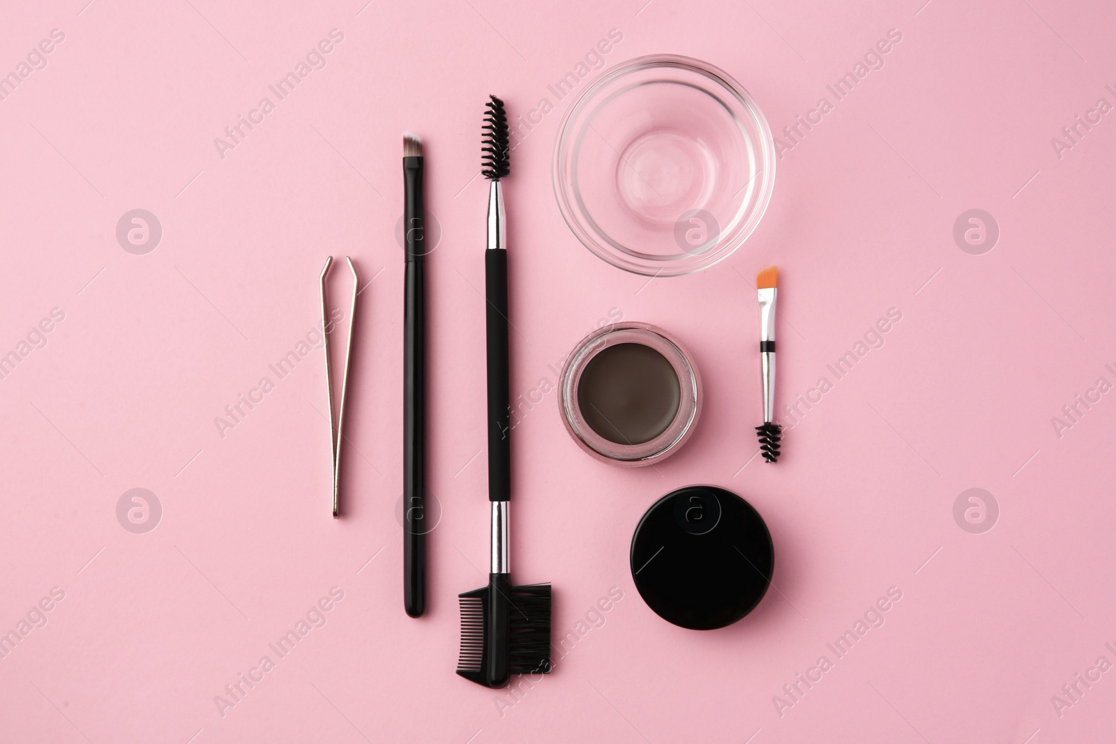 Photo of Eyebrow pomade with henna effect and professional tools on pink background, flat lay