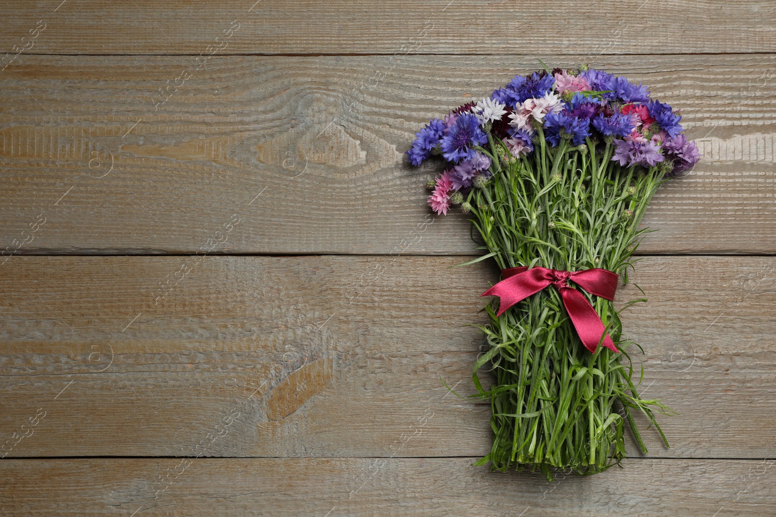 Photo of Bouquet of beautiful cornflowers on wooden table, top view. Space for text