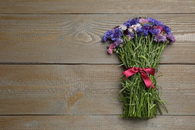 Photo of Bouquet of beautiful cornflowers on wooden table, top view. Space for text