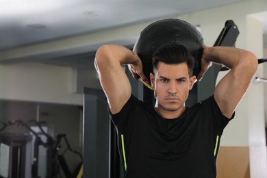 Athletic man with medicine ball in modern gym. Space for text