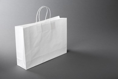 One white paper bag on grey background, space for text. Mockup for design