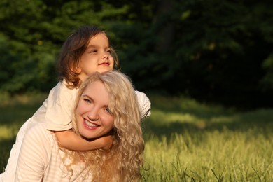 Photo of Happy mother with her cute daughter spending time together outdoors. Space for text