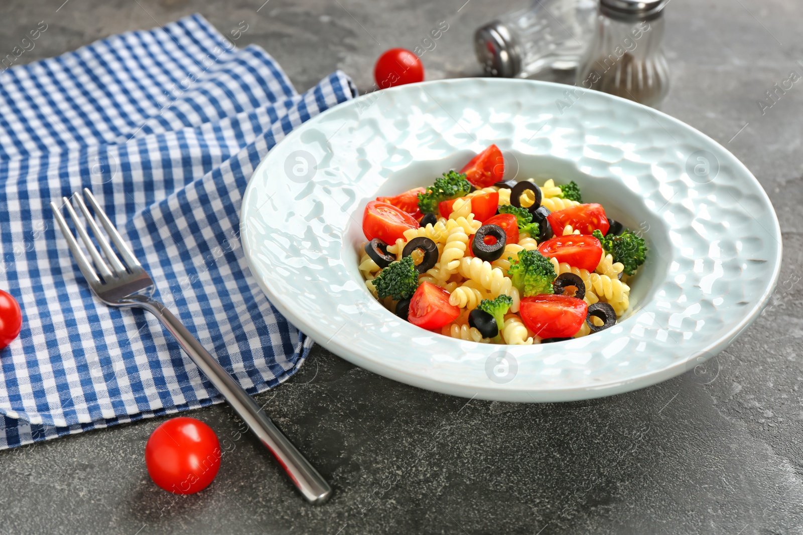 Photo of Plate with delicious pasta primavera on grey background