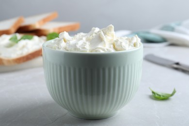 Bowl of tasty cream cheese on grey table