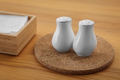 Photo of White ceramic salt and pepper shakers on wooden table