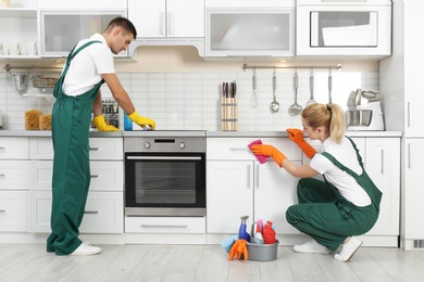 Photo of Team of janitors cleaning kitchen in house