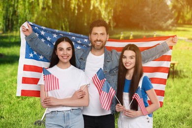 Image of 4th of July - Independence day of America. Happy family with national flags of United States in park