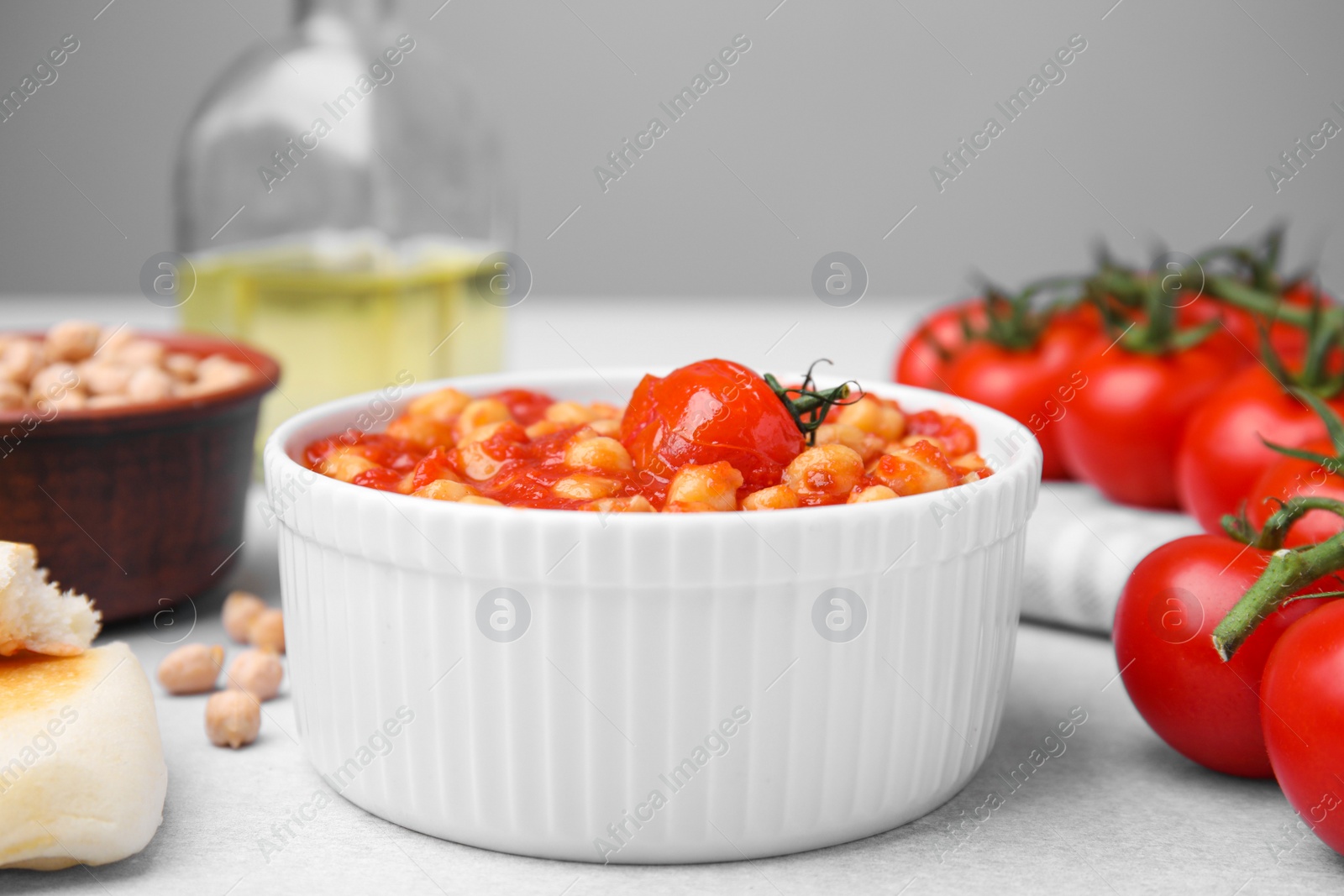 Photo of Delicious chickpea curry in bowl on light gray table, closeup