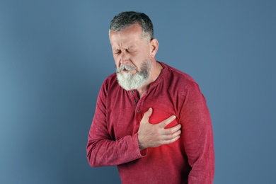 Photo of Mature man having heart attack on color background