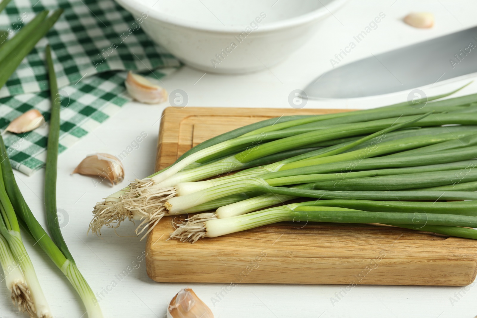 Photo of Fresh green spring onions and garlic cloves on white wooden table