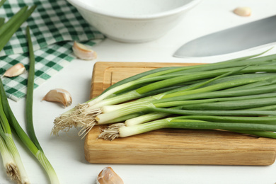 Photo of Fresh green spring onions and garlic cloves on white wooden table