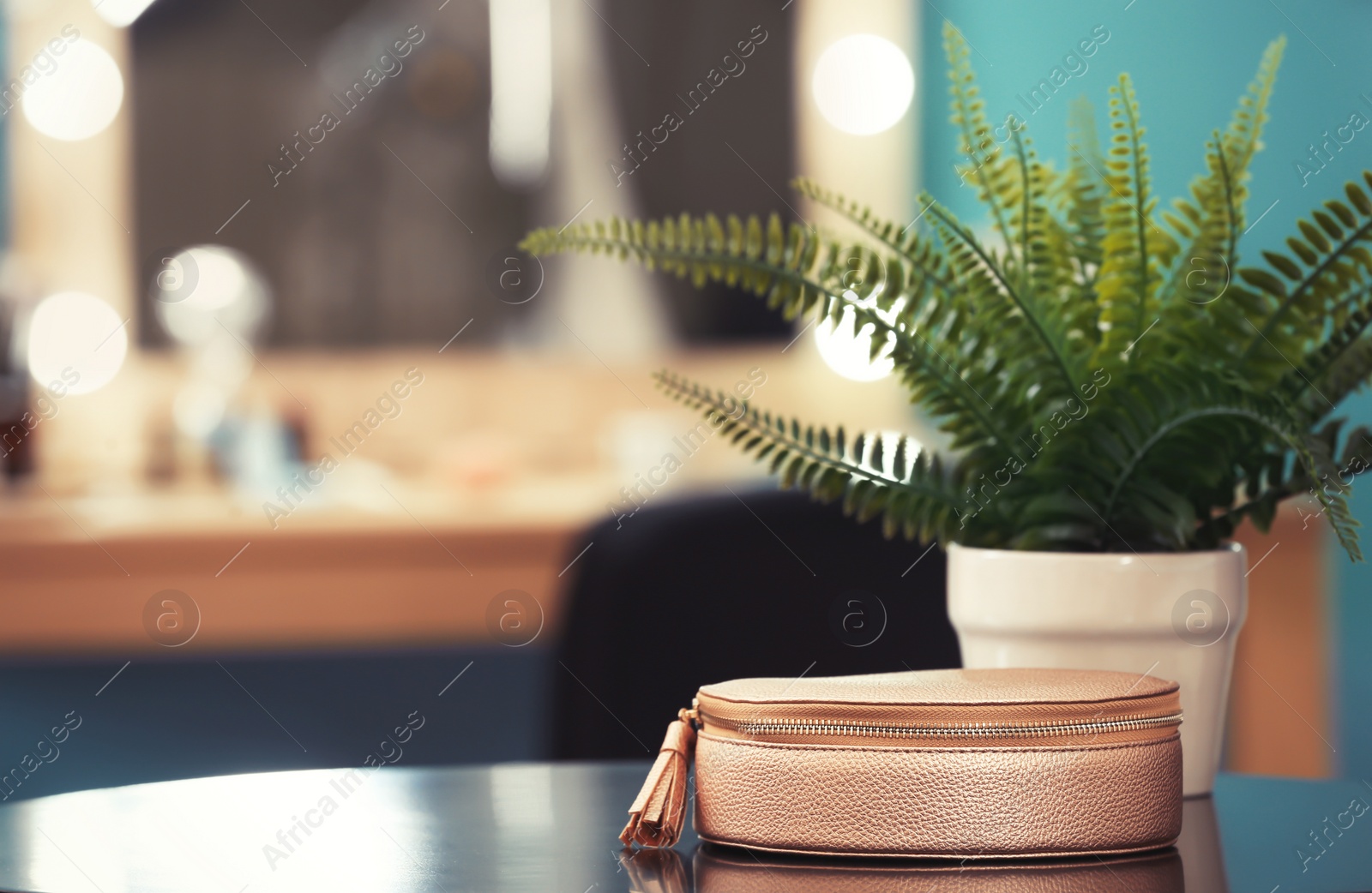 Photo of Cosmetic bag and plant on table in makeup room