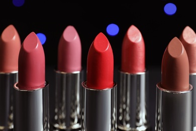 Photo of Different lipsticks against blurred lights. Cosmetic product