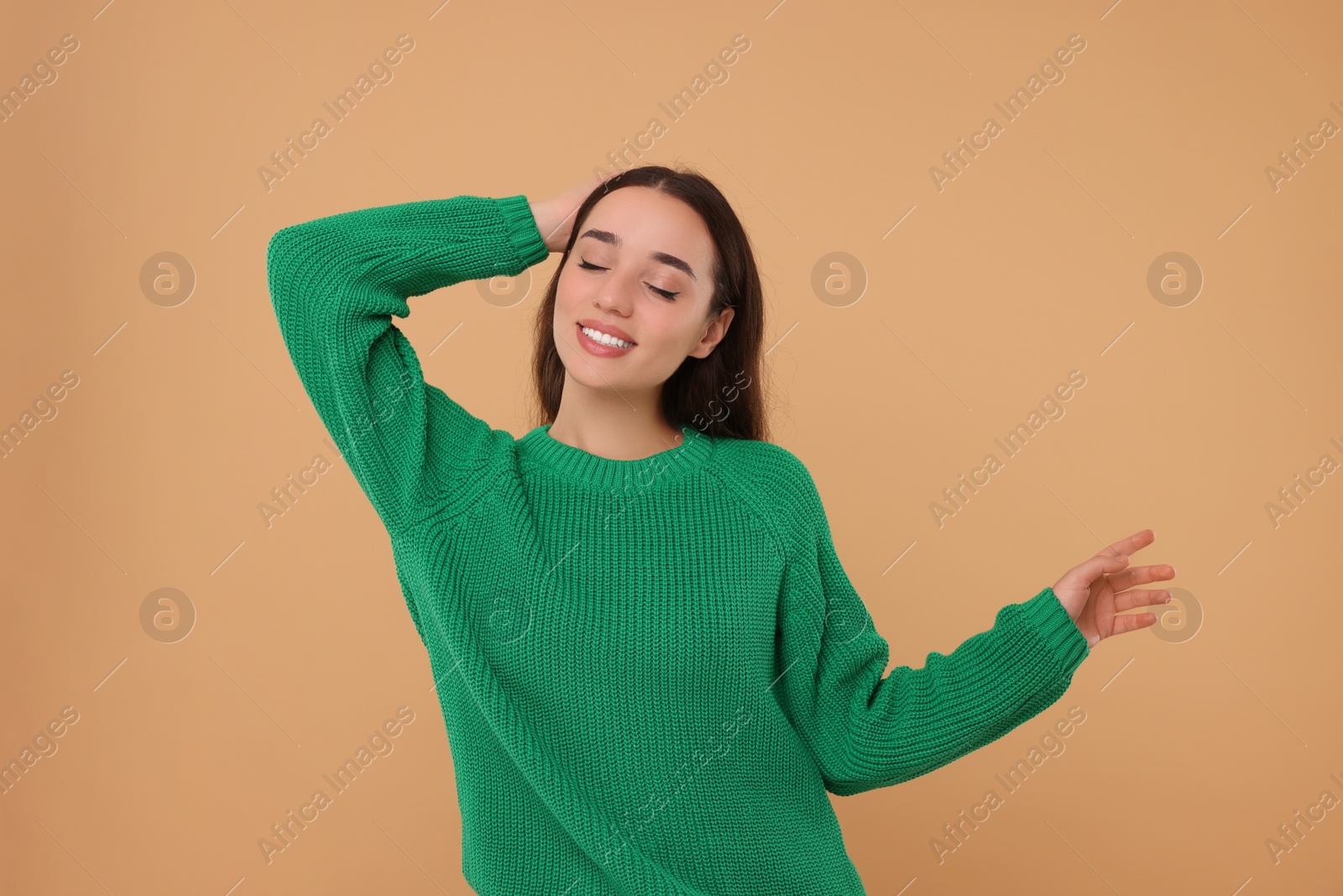 Photo of Beautiful young woman in stylish warm sweater on beige background