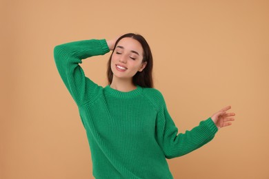 Photo of Beautiful young woman in stylish warm sweater on beige background