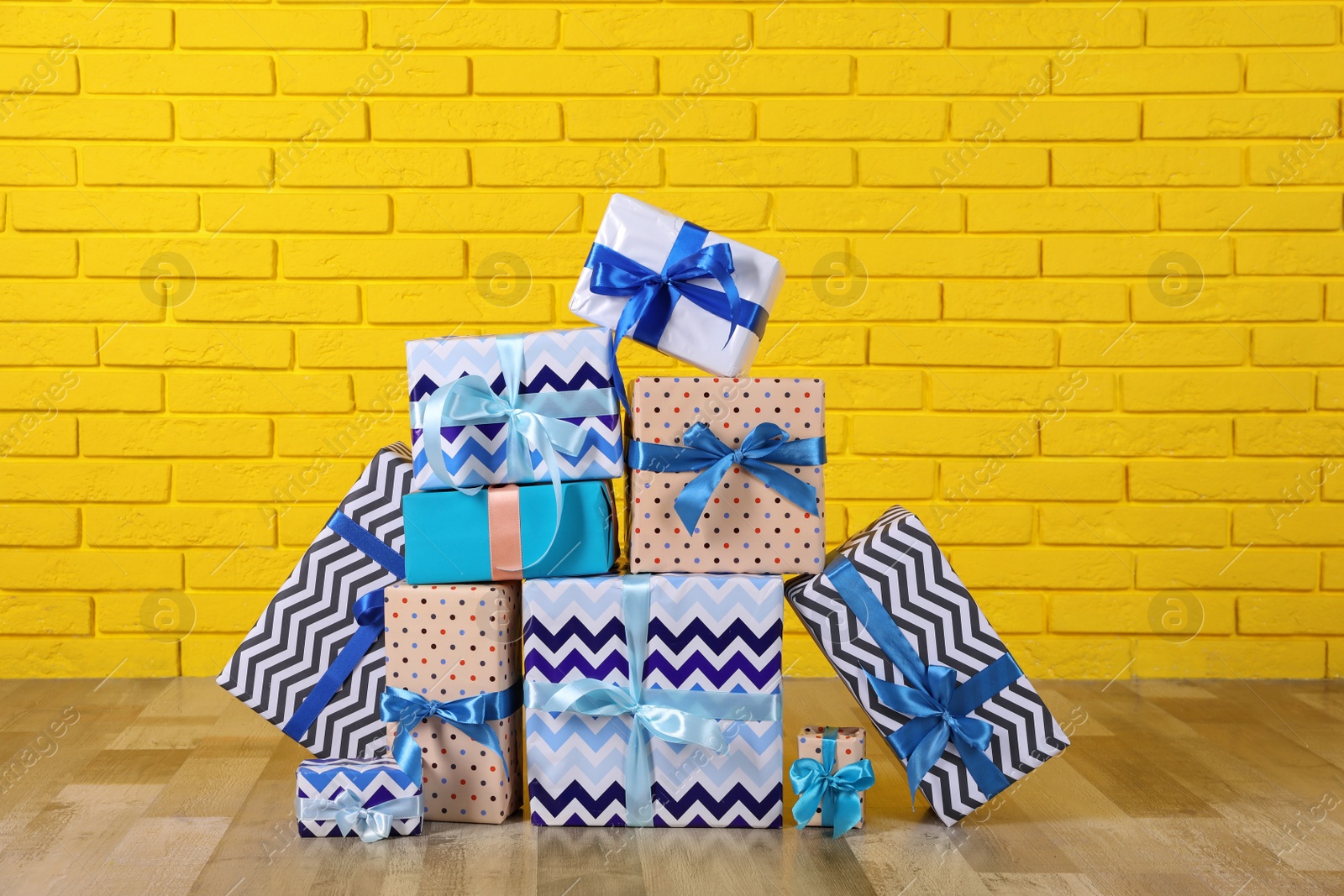 Photo of Many gift boxes near yellow brick wall