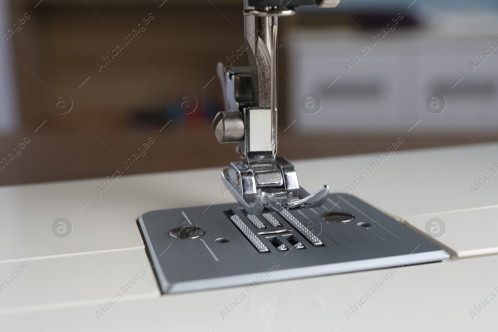 Photo of White sewing machine on blurred background, closeup