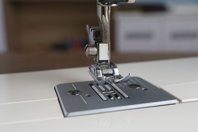 Photo of White sewing machine on blurred background, closeup